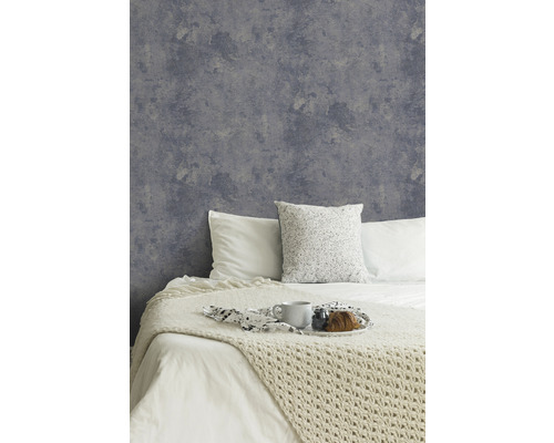 Schlafzimmer mit grauer Vliestapete im Betonlook und dekoriertem Bett