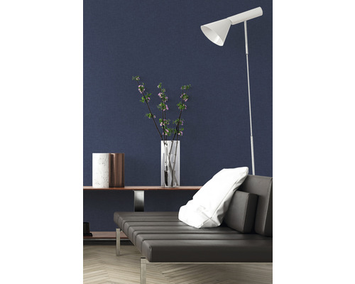 Modernes Interieur mit Sofa, Stehlampe und Dekorationsgegenständen vor einer dunklen Wand