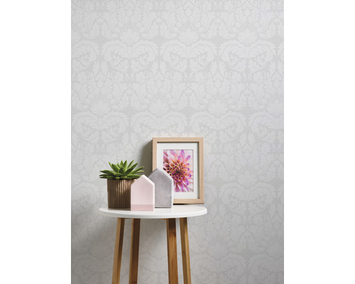 Scène avec papier peint à motifs, petite table, plante en pot, cadre photo et décoration