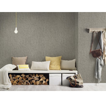 Wohnraum mit grauer Textiltapete, Sitzbank mit Kissen, Holzscheiten und Aufbewahrungsboxen