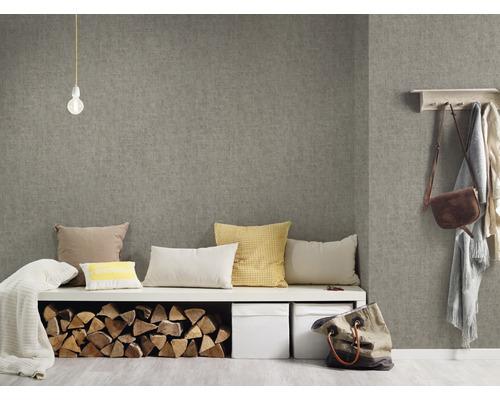 Pièce à vivre avec papier peint textile gris, banc avec coussins, bûches et boîtes de rangement