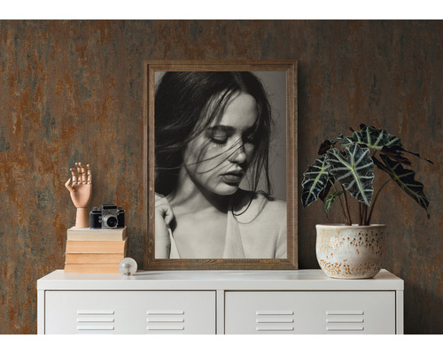 Dekorative Szene mit gerahmtem Porträt, Pflanze im Topf, Kameramodell und Holzhand auf einem weißen Schrank.