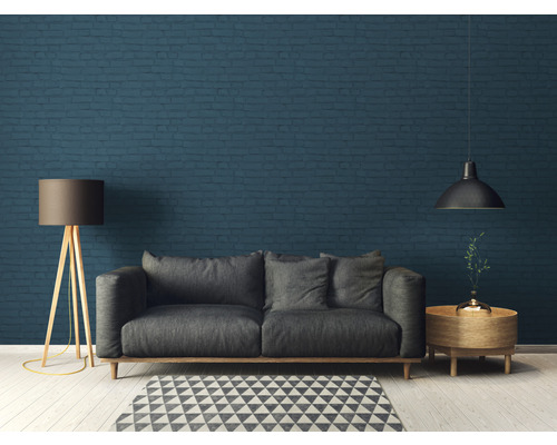 Salon avec canapé, lampadaire, table d''appoint et suspension devant un mur en briques