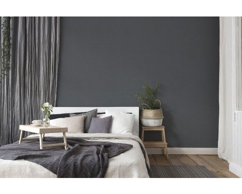 Schlafzimmer mit Bett, Nachttisch, Pflanze und Vorhängen