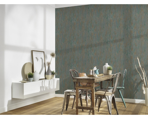 Esszimmer mit rustikalem Holztisch und industriellen Metallstühlen vor einer Wand mit grüner und brauner Muster-Tapete.