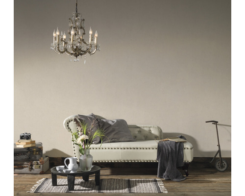 Salon avec lustre en cristal, canapé capitonné, petite table, décoration et trottinette pour enfants