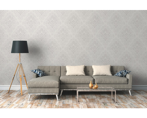 Wohnzimmer mit Couch, Tisch und Stehlampe vor gemusterter Tapete