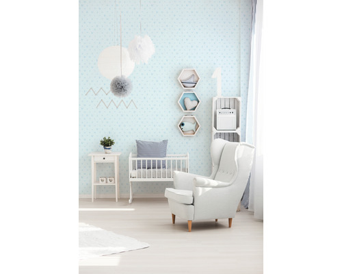 Helles Kinderzimmer mit Babybett, Sessel, Kommode und Wanddekorationen.