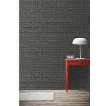 Zimmer mit grauer Backsteinwand, rotem Tisch und Lampe.