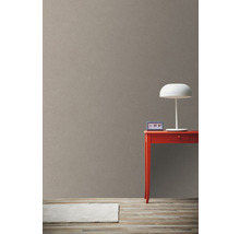 Helle Zimmeransicht mit brauner Tapete, rotem Tisch und weißer Lampe