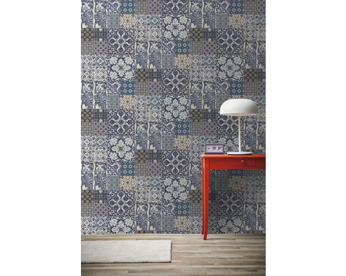 Raumansicht mit Patchwork-Tapete, rotem Tisch und Lampe