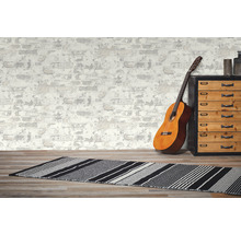Dekoratives Zimmer mit Gitarre, Teppich und Kommode vor einer Tapete im Mauerwerk-Design.