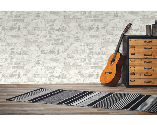 Dekoratives Zimmer mit Gitarre, Teppich und Kommode vor einer Tapete im Mauerwerk-Design.