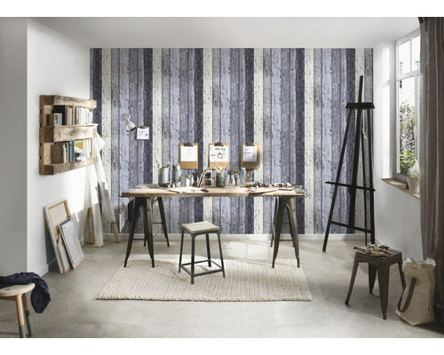 Atelier mit Staffelei, Tisch, Hocker und Regal vor einer Tapete mit Holzoptik