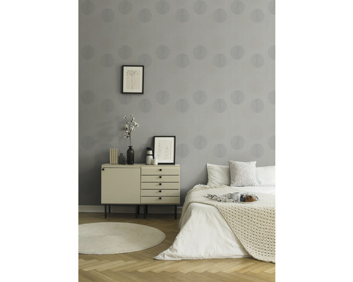 Schlafzimmer mit grauer Tapete, Kommode und Bett.