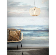 Dekoratives Interieur mit Rattanmöbeln, Textilkissen, Pendelleuchte und Fototapete mit Landschaftsmotiv