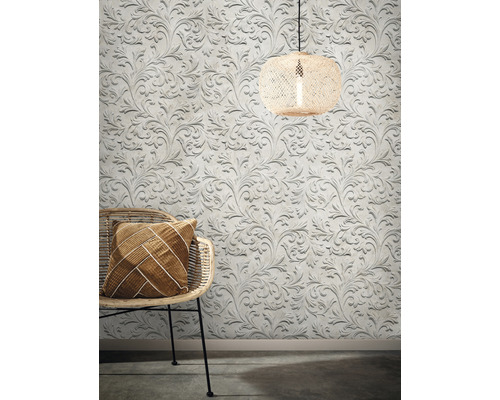 Dekoratives Wohnambiente mit floral gemusterter Tapete, Rattansessel und Lampe