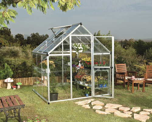 Gewächshaus mit Pflanzen und geöffneter Tür im Garten.