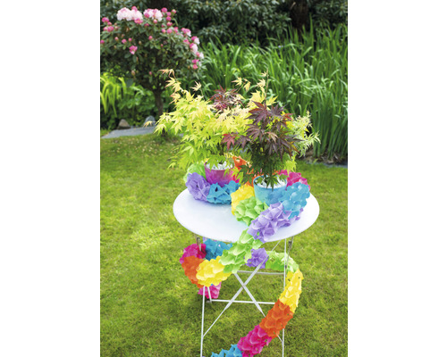 Table de jardin décorée avec des érables et une guirlande de fleurs