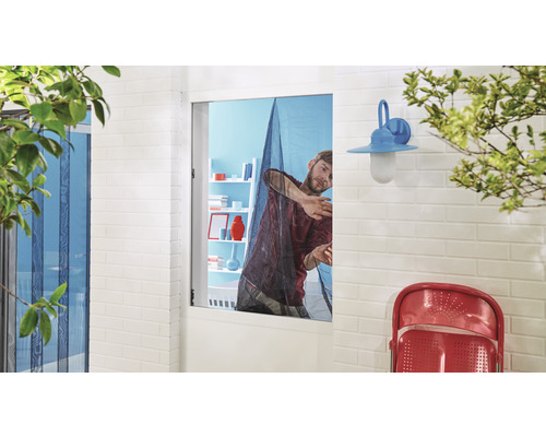 Un homme fixe une moustiquaire à une fenêtre.