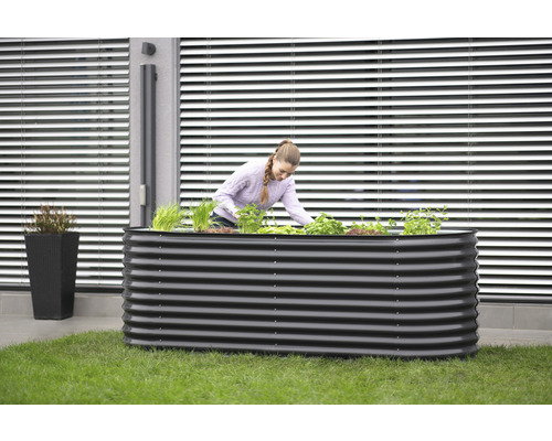 Hochbeet aus Metall mit Frau beim Bepflanzen im Garten
