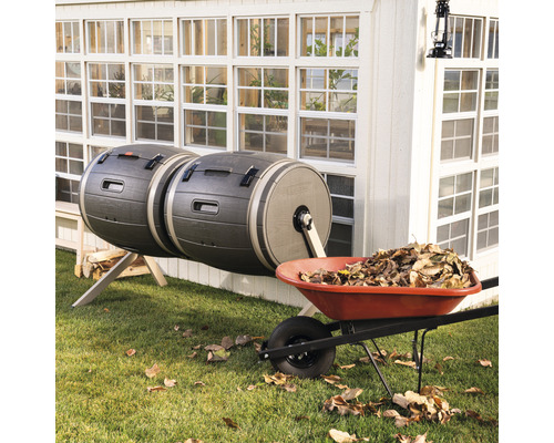 Doppelter Kompostbehälter und Schubkarre mit Laub im Garten