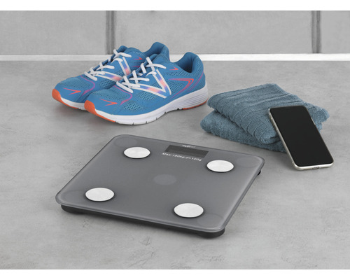 Personenwaage mit Sportschuhen, Handtuch und Smartphone