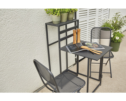 Scène de jardin avec table, deux chaises et un support à plantes sur une terrasse.