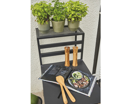 Table de cuisine avec herbes aromatiques, livre de cuisine, cuillères de cuisine et moulins à épices