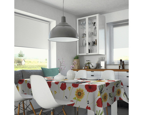 Salle à manger lumineuse avec table à manger, chaises et nappe à motifs floraux.