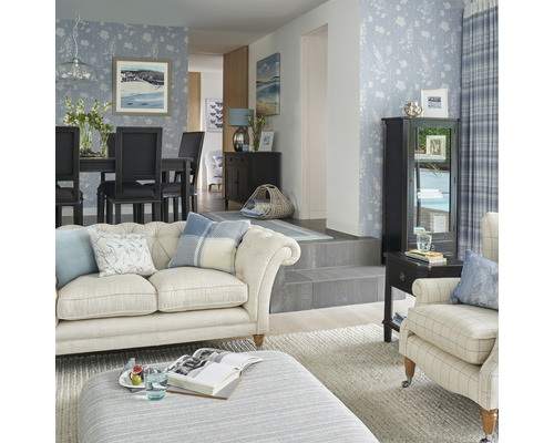 Helles Wohnzimmer mit floraler Tapete, Sofa, Sessel, Esstisch und Dekorationen