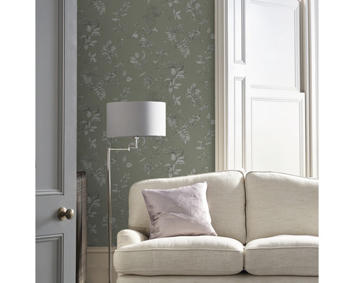 Wohnzimmer mit Couch, Stehlampe und floral gemusterter Tapete
