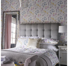Chambre lumineuse avec papier peint à motifs floraux, tête de lit rembourrée et miroir