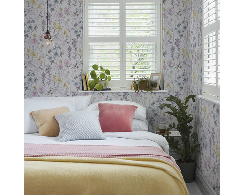 Chambre avec papier peint à fleurs, lit, coussins et fenêtre avec volets