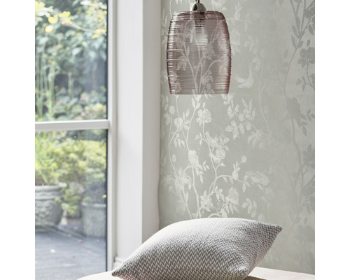 Lampe suspendue et papier peint à motifs floraux dans une pièce lumineuse.