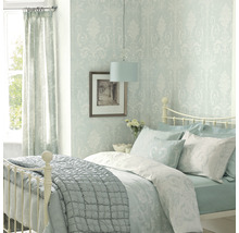 Chambre lumineuse avec lit, papier peint à motifs, rideaux et lampe