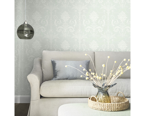 Wohnzimmer mit gemusterter Tapete, Sofa, Kissen, Tischdekoration und Hängelampe