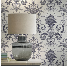 Pièce décorative avec une lampe de table devant un papier peint à motifs floraux.