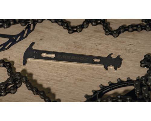 Jauge d''usure de chaîne de vélo de la marque BikeBroz à côté d''une chaîne de vélo et d''un plateau