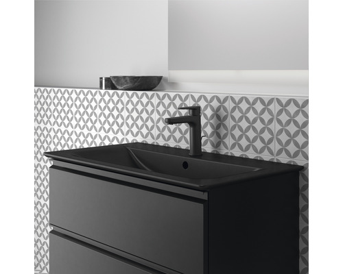 Meuble-lavabo noir avec robinetterie et mur de carreaux à motifs