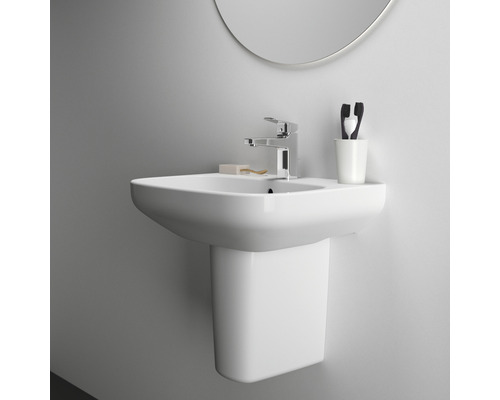 Weißes Waschbecken mit Armatur, Zahnputzbecher und Spiegel an einer Wand montiert.