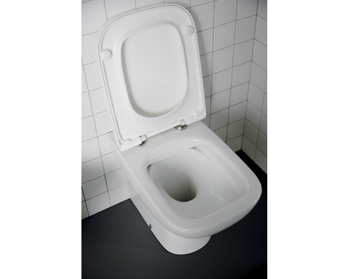 Toilettes sur pied blanches avec couvercle de toilettes ouvert devant des carreaux blancs
