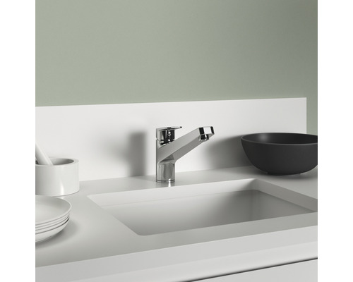 Ein Waschbecken mit Armatur und Accessoires im Badezimmer.