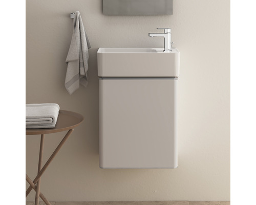 Salle de bains avec meuble-lavabo suspendu, robinetterie, serviette et table d''appoint