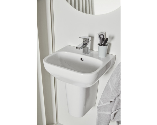Lavabo en céramique avec robinet et espace de rangement dans la salle de bain