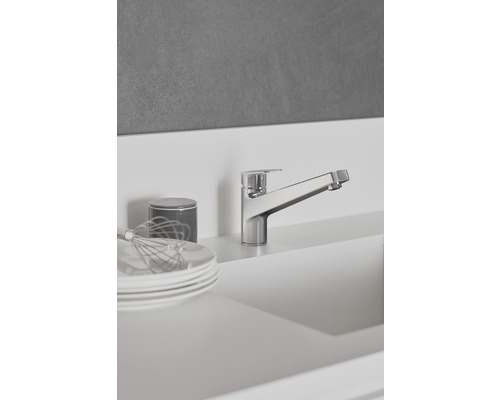 Küchenszene mit Armatur, Tellern und Küchenutensilien.