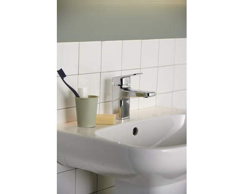 Lavabo avec robinet, brosse à dents, gobelet et savon dans la salle de bain