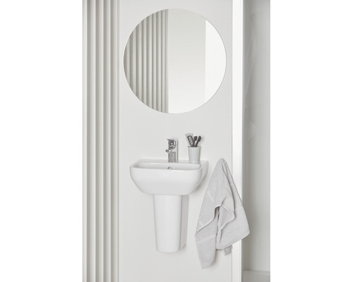 Salle de bains lumineuse avec lavabo, miroir et serviette