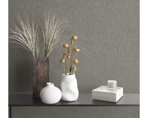 Dekorative Elemente auf einem Tisch: Vasen, Trockenblumen, Buch und Kerze.