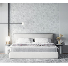 Chambre avec lit, tables de chevet, lampes et papier peint fleuri pour une ambiance lumineuse et spacieuse.